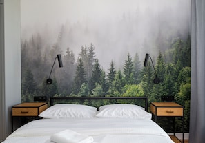 A bedroom with a bed, two bedside tables, and a wall mural of a forest. - Mokotów Residence Apartment (Warszawa)
