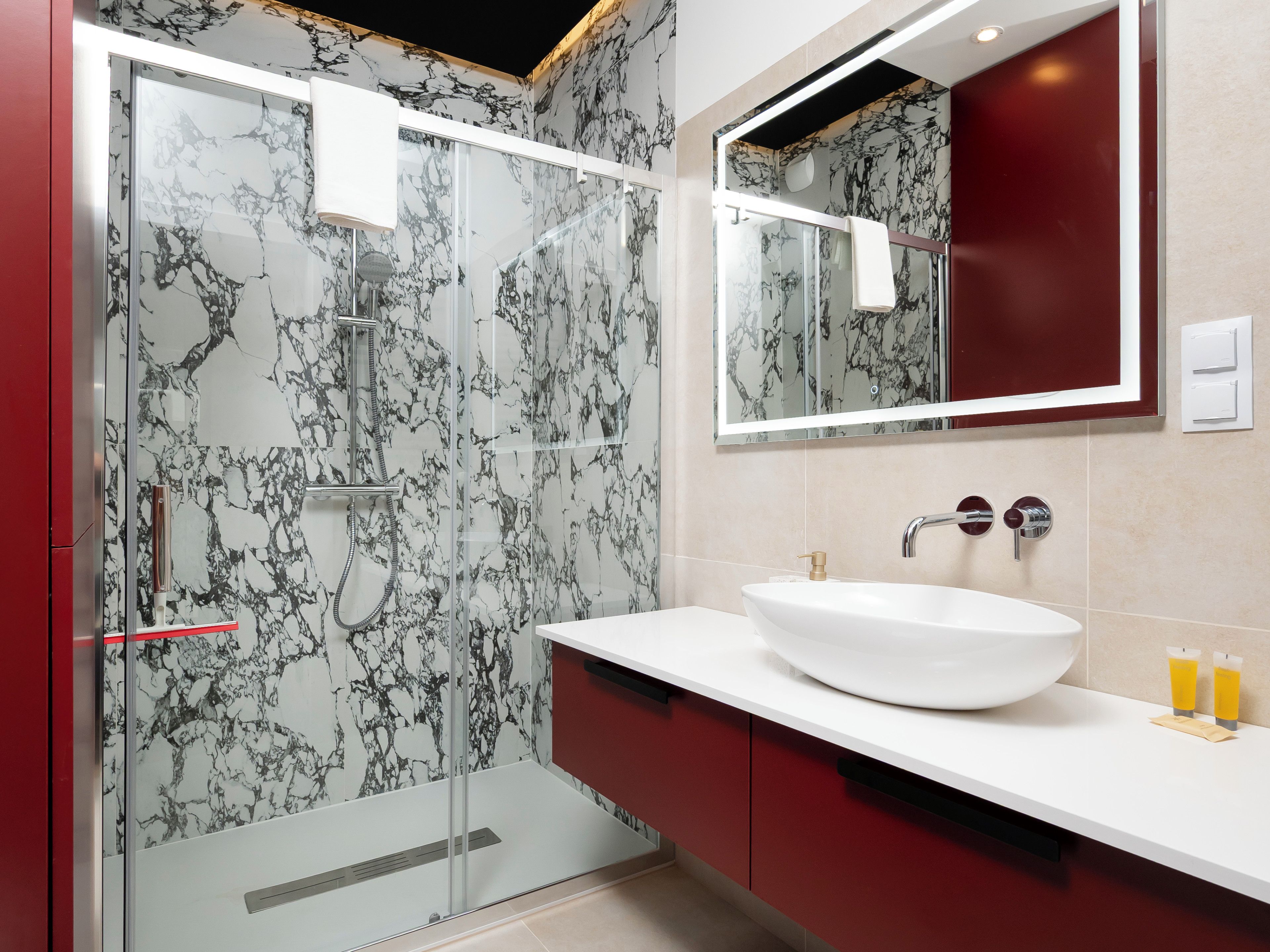 A modern bathroom with a glass-enclosed shower, a white sink, and a mirror above it.