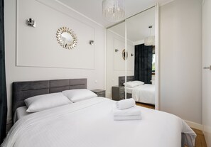 Una habitación de hotel moderna con una cama grande, un espejo y apliques decorativos.