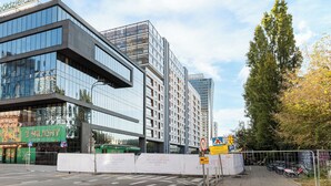 A modern building with large glass windows and a sign for 'Blisko 3 Miliony Klientów'. - Wola Grzybowska Lavish Apartment (Warszawa)