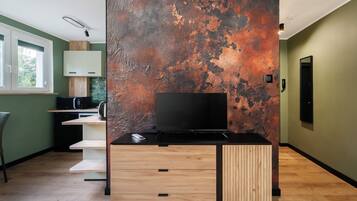 A modern kitchen with a flat-screen TV, wooden cabinetry, and a rustic wall.