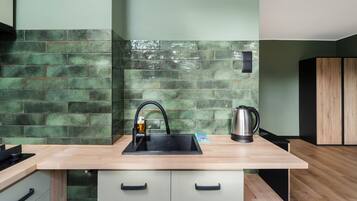 A kitchen with a modern design, featuring a sink, a kettle, and a wooden countertop.
