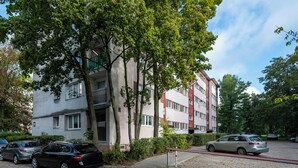 Un edificio residencial de varios pisos con un área de estacionamiento al frente.