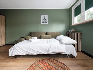 A bedroom with a bed, pillows, a bedside table, a window, and a framed picture on the wall. - Aleksandrowska City Prestige Studio (Łódź)
