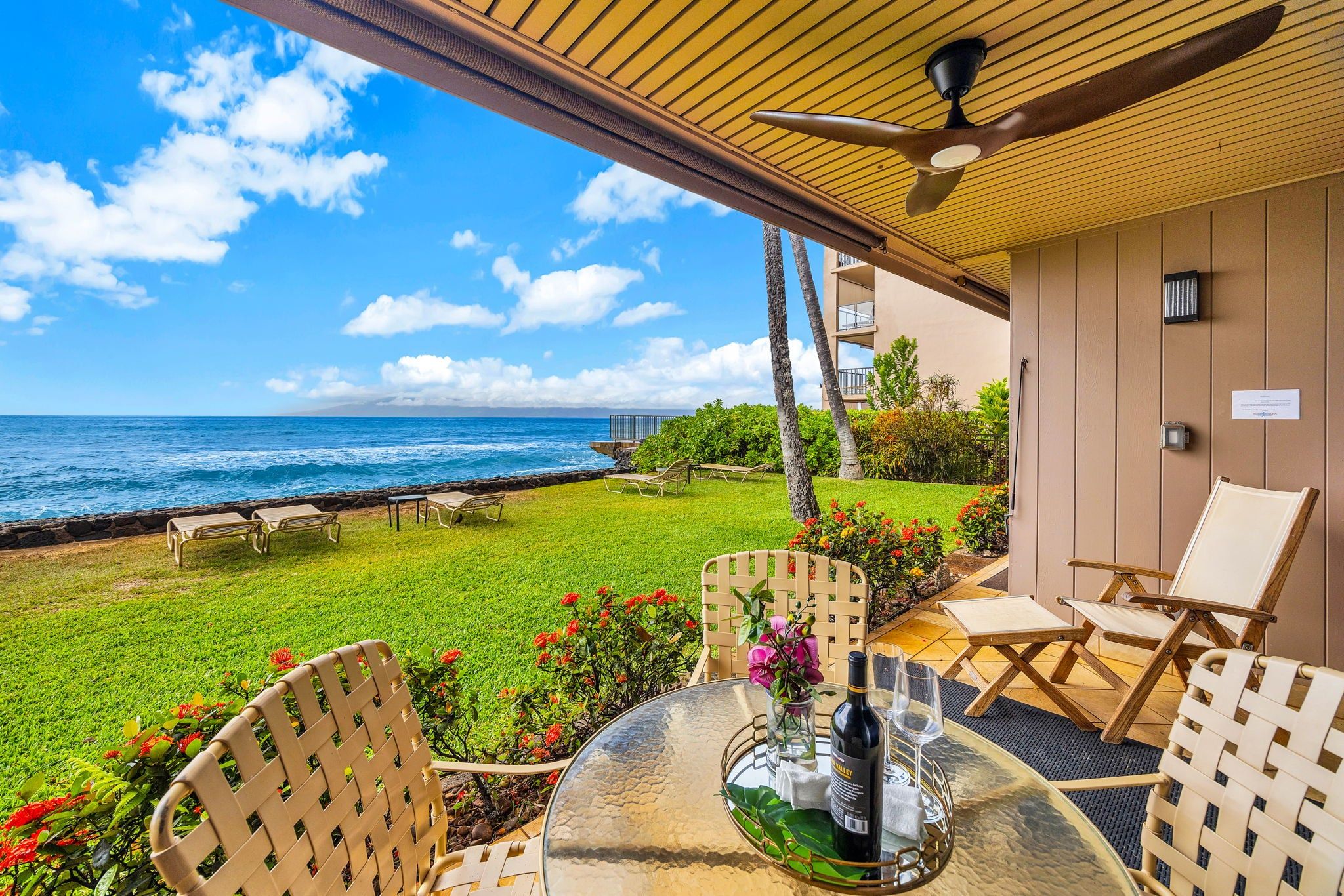 A patio with a table, chairs, and a view of the ocean.