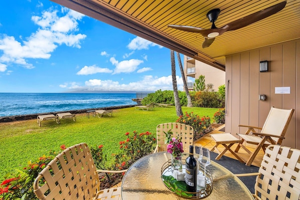 A patio with a table, chairs, and a view of the ocean. - Oceanfront Lahaina Oasis 1 Bedroom (Lahaina)