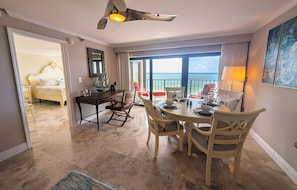 A hotel room with a dining area, a bed, and a view of the sea. - Ocean-front 2BR condo in Islamorada with pool, hot tub, gym, and balcony. (Islamorada)