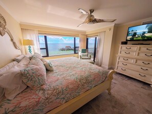 Ein Schlafzimmer mit Bett, Kommode, Fernseher und Meerblick.