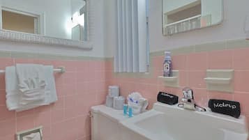 Un bagno con un lavandino bianco, due specchi, un water e piastrelle rosa.