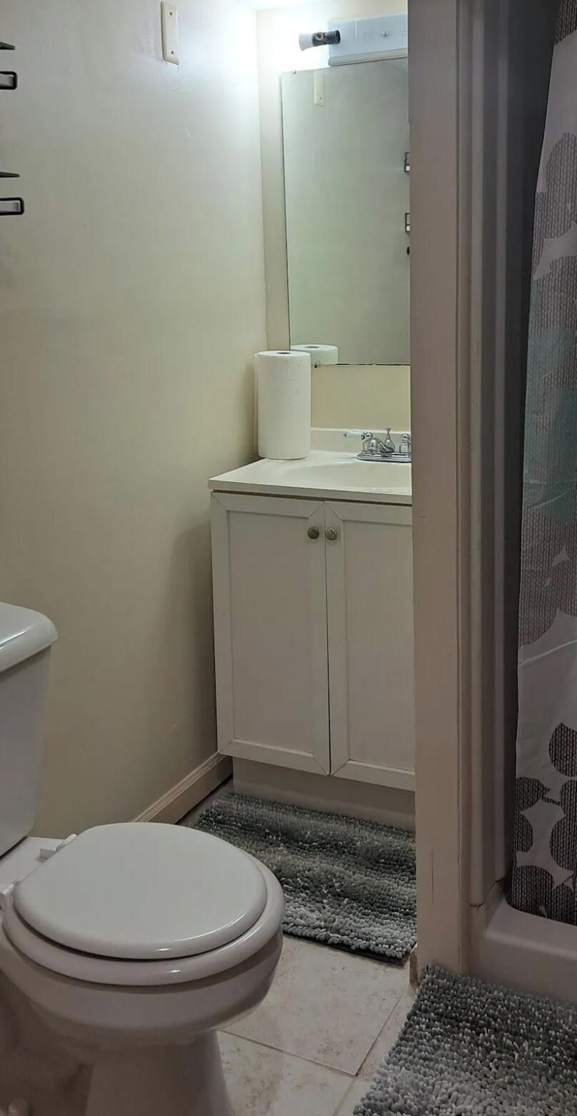 A bathroom with a toilet, a sink, and a mirror.