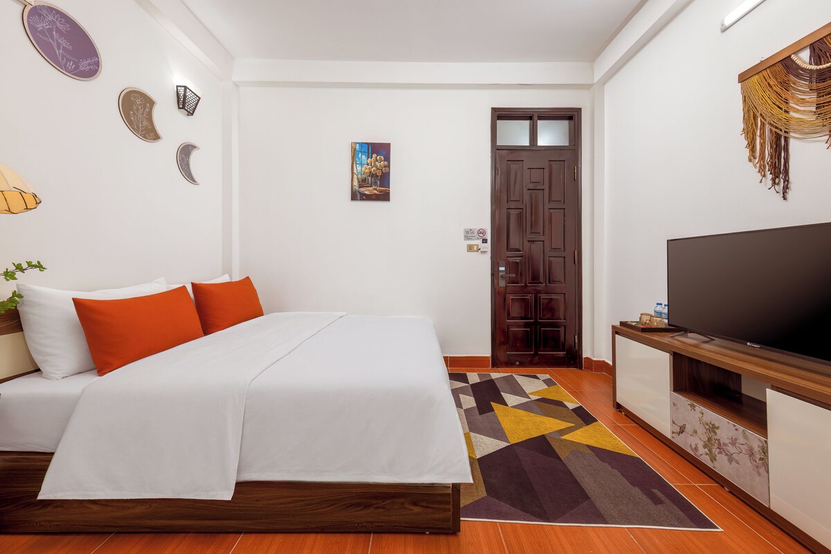 A hotel room with a bed, a TV, and a door.