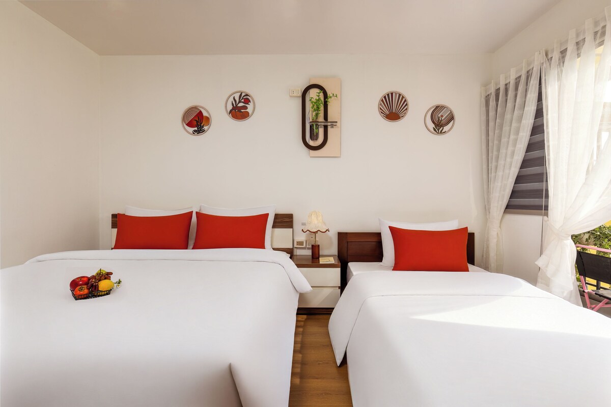 A hotel room with two beds, a nightstand, a lamp, and decorative wall art.
