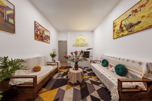 A modern living room with a sofa, a coffee table, and a painting on the wall. - Aura Retreat Hanoi Central (Ha Noi)