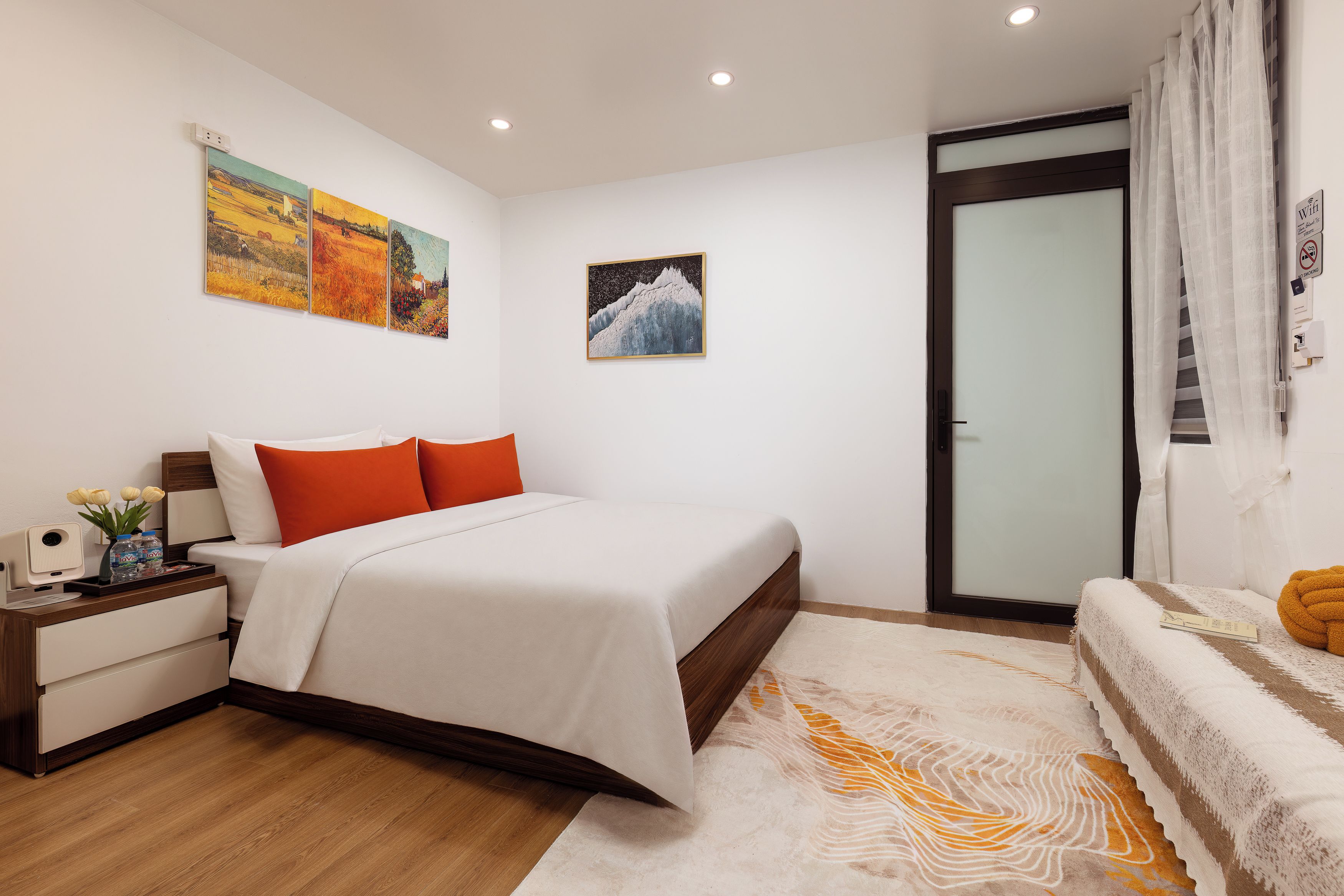 A hotel room with a bed, bedside table, and artwork on the wall.