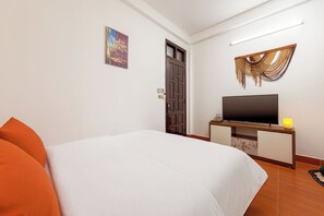 A hotel room with a bed, a television on a wooden stand, a door, and a wall-mounted light fixture. - Aura Retreat Hanoi Central (Ha Noi)