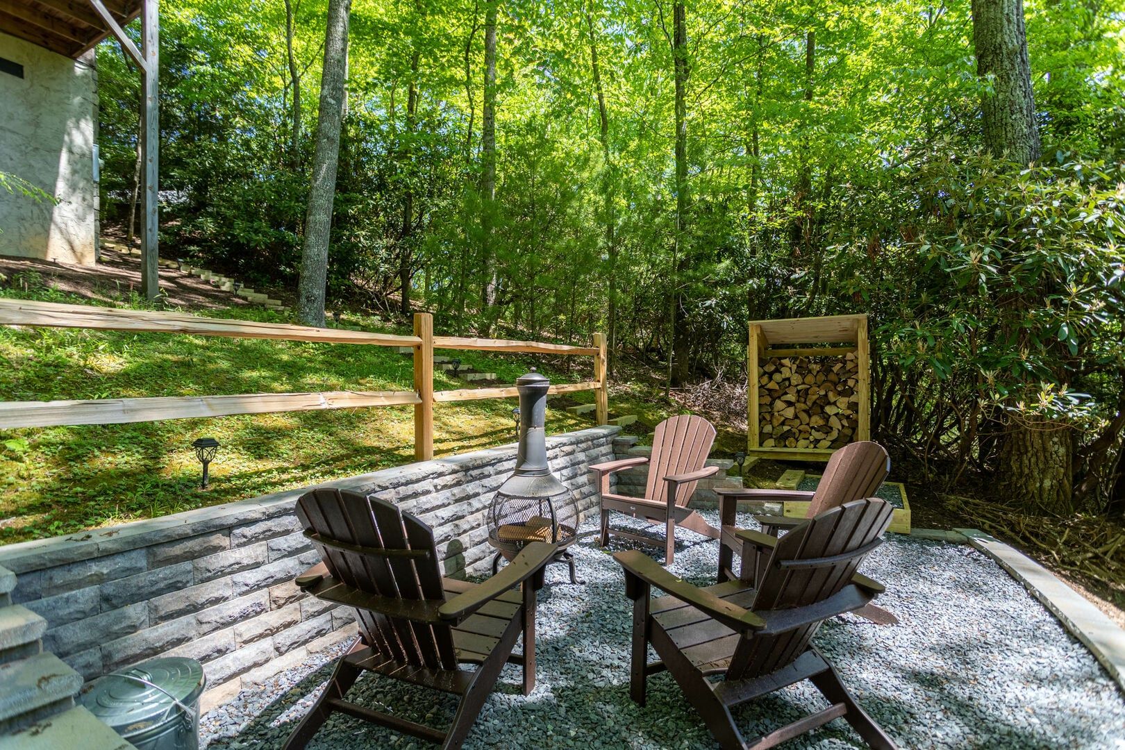 Un espace extérieur aménagé avec des chaises Adirondack, une table en métal et un foyer.