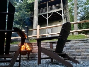 A rustic outdoor seating area with a fire feature, wooden chairs, and a stone wall. - Private Mountain Retreat with Hot Tub, Fire Pit & Forest Views (Vilas)