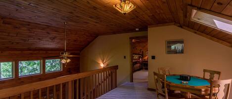 A wooden interior with a dining area, a staircase, and a view of the outdoors.