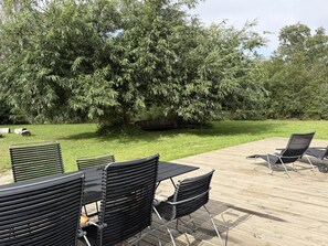 An outdoor seating area with tables and chairs, surrounded by a well-maintained lawn and a large tree. - "Pirka" - 500m from the sea by Interhome (Væggerløse)