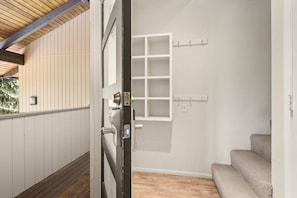 A room with a wooden floor, a white door, a window with a view of trees, and a wall-mounted light fixture. - Cozy Snowmass Retreat with Vaulted Ceilings, Gas Fireplace, Outdoor HT. On Free Shuttle (Snowmass Village)