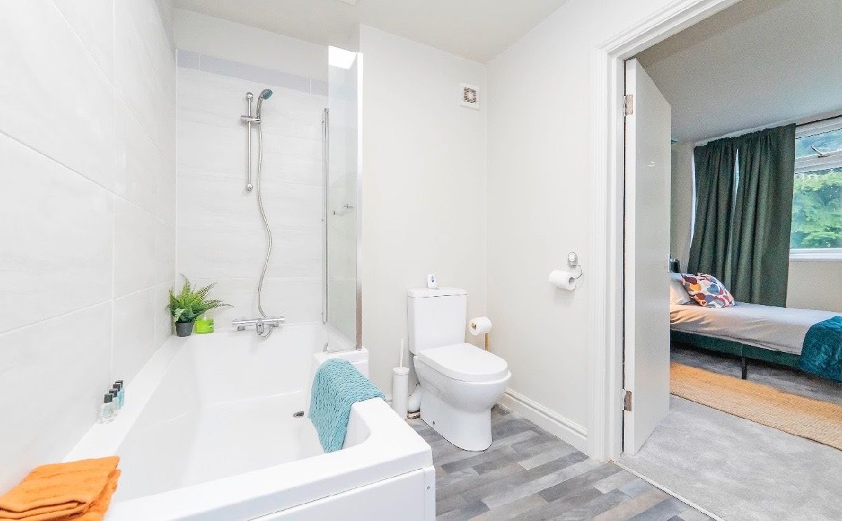 A modern bathroom with a bathtub, toilet, and shower.