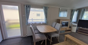 A compact living space with a dining table, chairs, a television, and a fireplace.