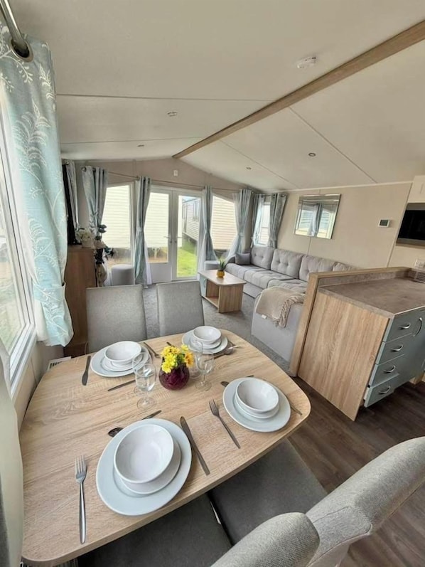 A compact RV interior with a dining area, kitchenette, and seating space.