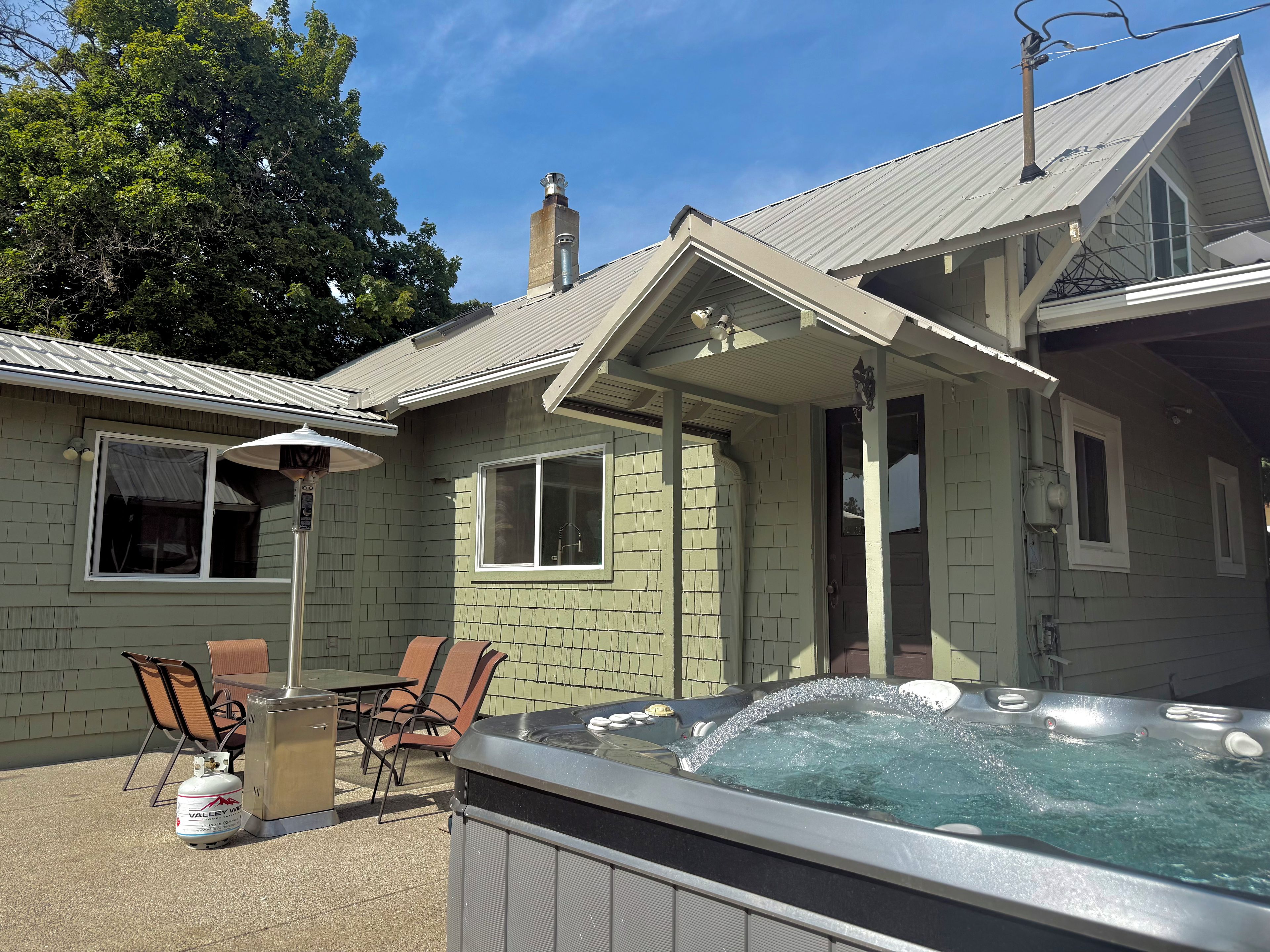 A house with a hot tub, outdoor seating, and a chimney.