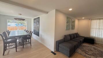 A modern living room with a dining area, a gray sectional sofa, and artwork on the walls.