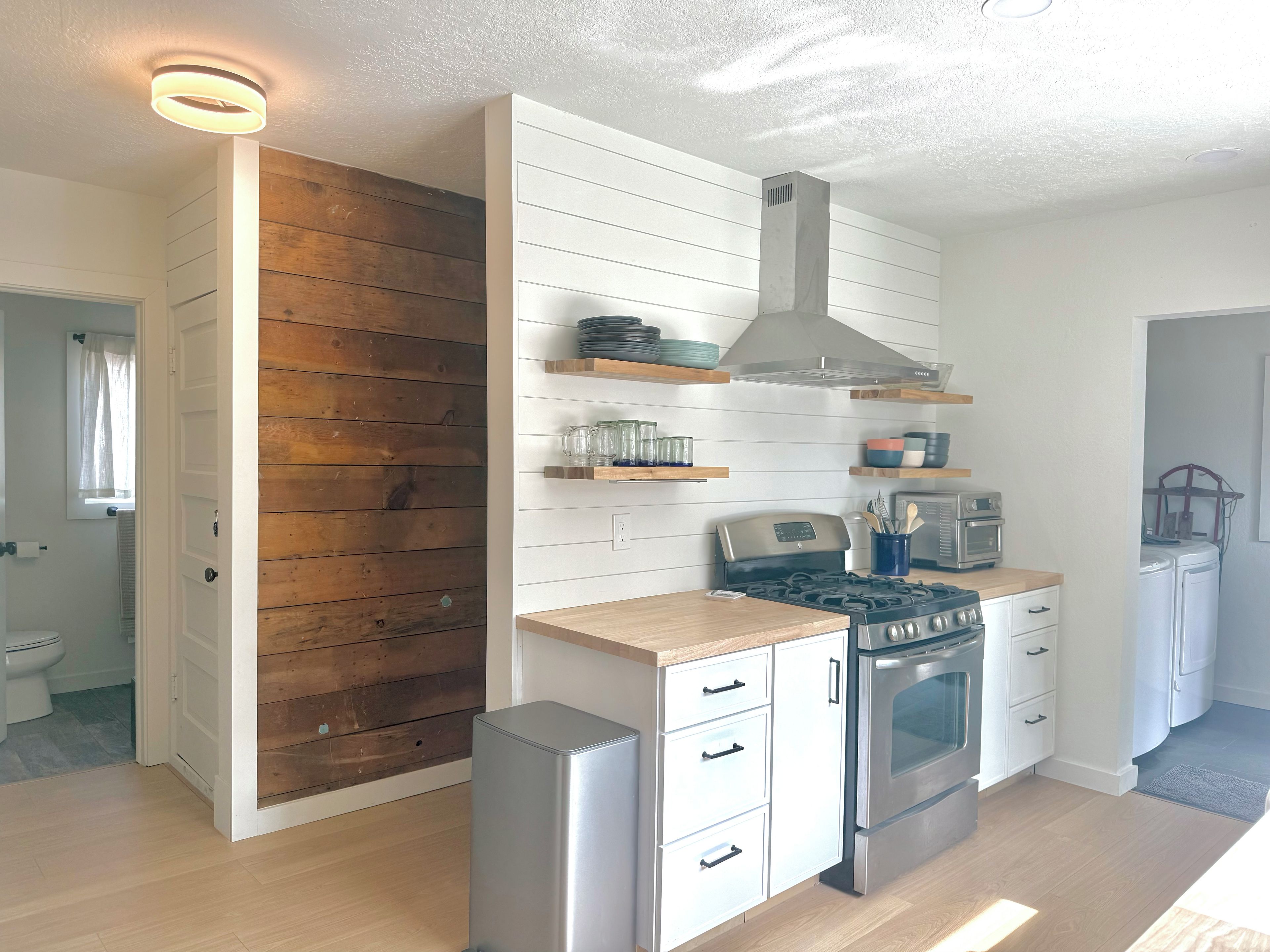 A modern kitchen with white cabinetry, wooden accents, a stainless steel stove, and a built-in oven.
