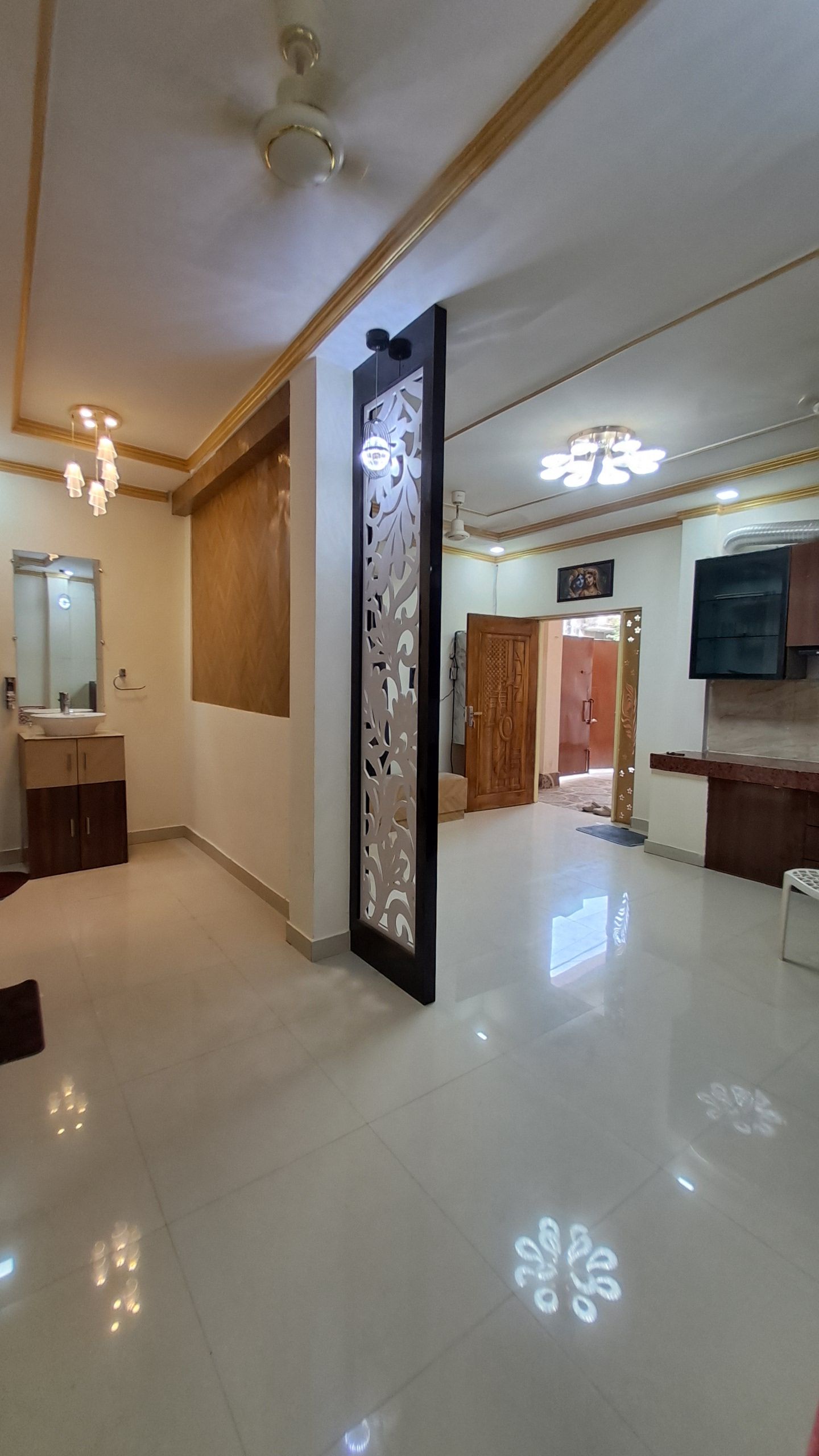 A spacious room with a large mirror, a decorative panel, and a ceiling with recessed lighting.