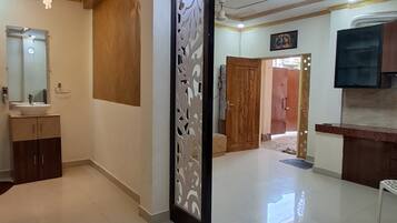 A spacious room with a large mirror, a decorative panel, and a ceiling with recessed lighting.