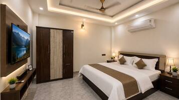 A hotel room with a large bed, a TV mounted on the wall, a wardrobe, and an air conditioning unit.