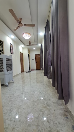 Passadís amb ventilador de sostre, il·luminació empotrada, radiador i una porta al final.