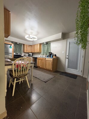 A kitchen with wooden cabinets, a dining table with chairs, a refrigerator, and a microwave. - Find comfort and relaxation when experiencing your vacation (Twin Falls)