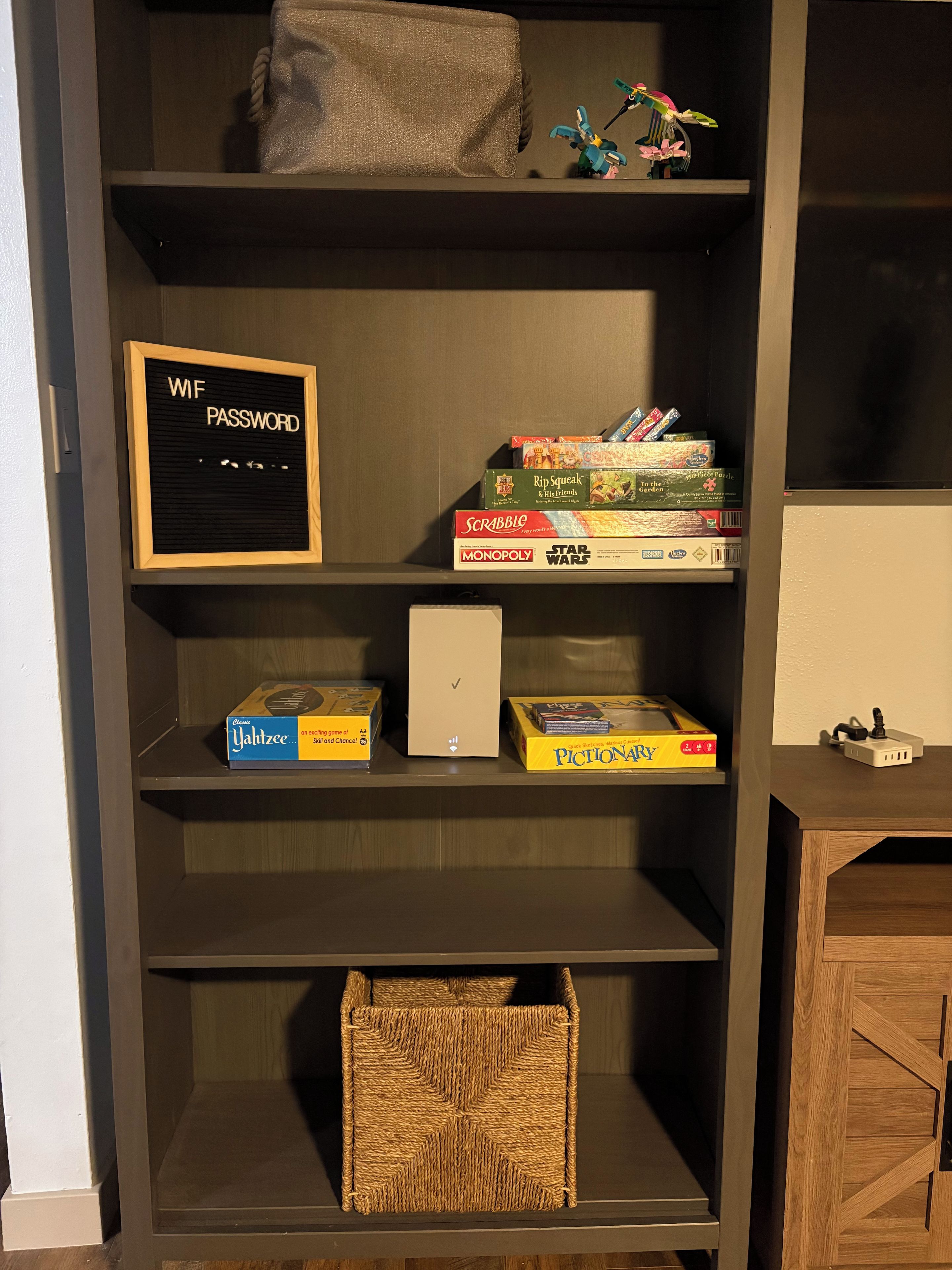 Una estantería con varios juegos de mesa y un cartel enmarcado.