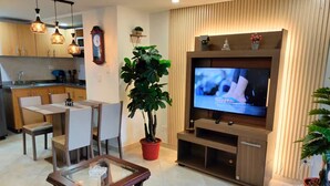 Una sala de estar moderna con comedor, un televisor de pantalla plana grande, armarios de madera y plantas en macetas.