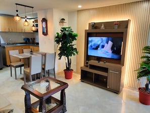 A modern living room with a dining area, a large flat-screen TV, wooden cabinets, and potted plants. - Exclusive, luxurious, centrally located apartment — serene and comfortable 302 (Medellín)