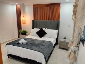 A modern bedroom with a bed, bedside tables, a hanging light fixture, and a wooden panel wall. - Exclusive, luxurious, centrally located apartment — serene and comfortable 302 (Medellín)