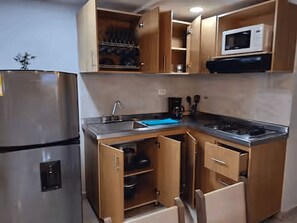 A compact kitchen with a built-in microwave, a sink, and wooden cabinets. - Exclusive, luxurious, centrally located apartment — serene and comfortable 302 (Medellín)