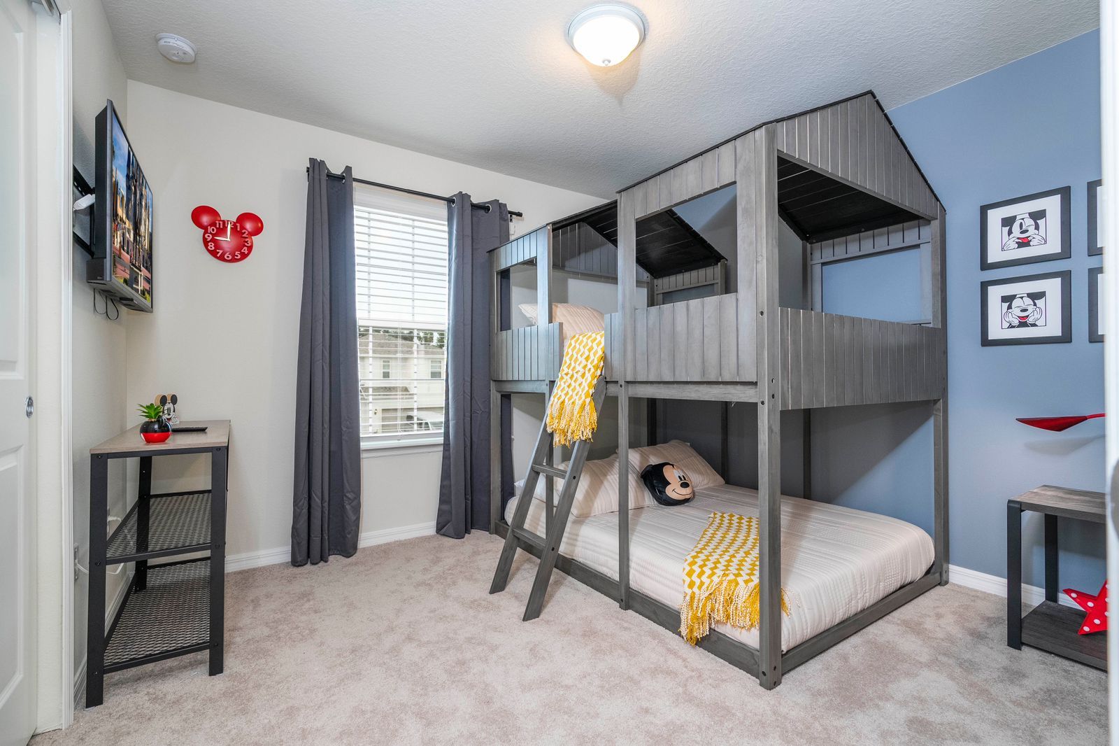 A bunk bed room with a ladder, a small table with a plant, and a window with curtains.
