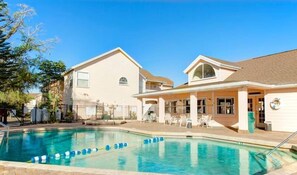 Un edificio residencial con piscina, mobiliario exterior y un patio cercado.