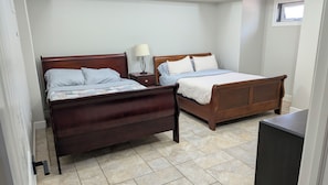 A bedroom with two wooden beds, a nightstand, a lamp, and a window. - Hillside Hideaway (Bentonville)