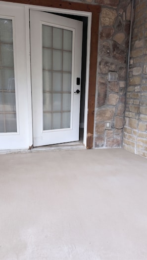 A room with a white door, a stone wall, and a concrete floor.