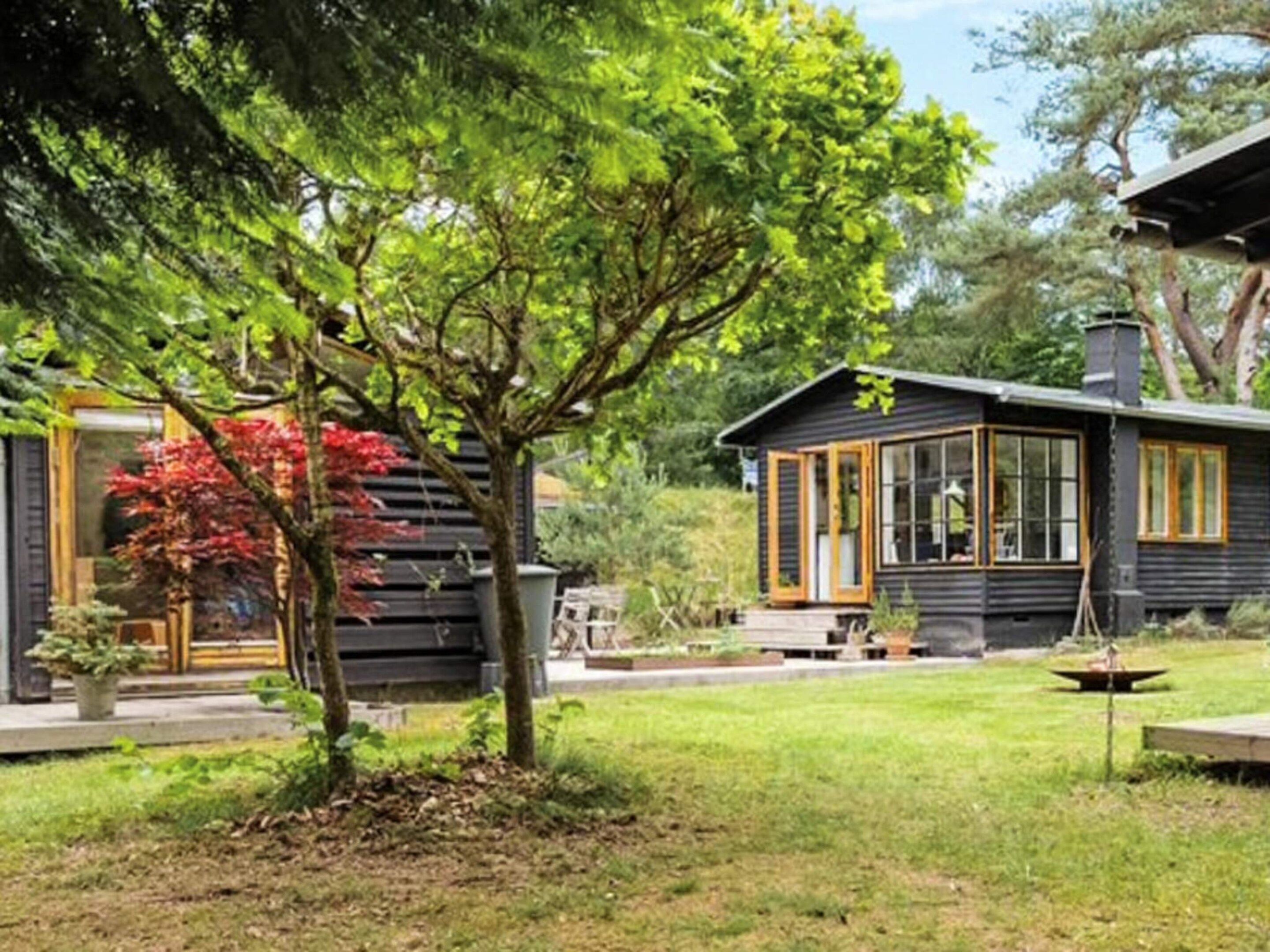A cabin with a covered porch, a small garden, and a clear sky.