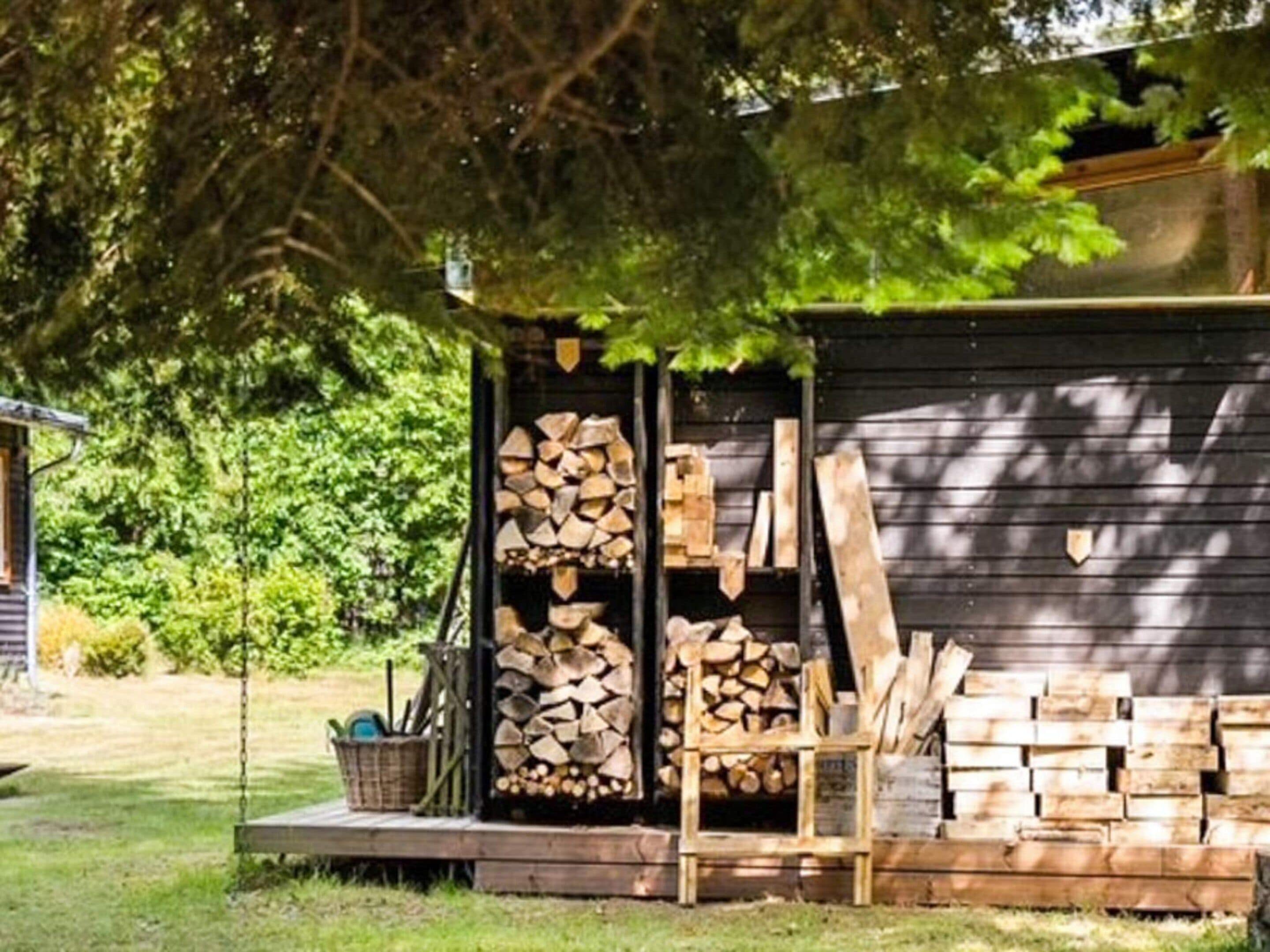 Ein Holzshed mit gestapeltem Brennholz und einem Stuhl davor.