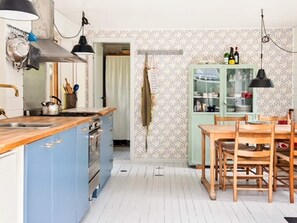 A kitchen with a wooden countertop, a stove, and a dining area with a table and chairs. - 8 Person Holiday Home in Frederiksvaerk (Frederiksvaerk)