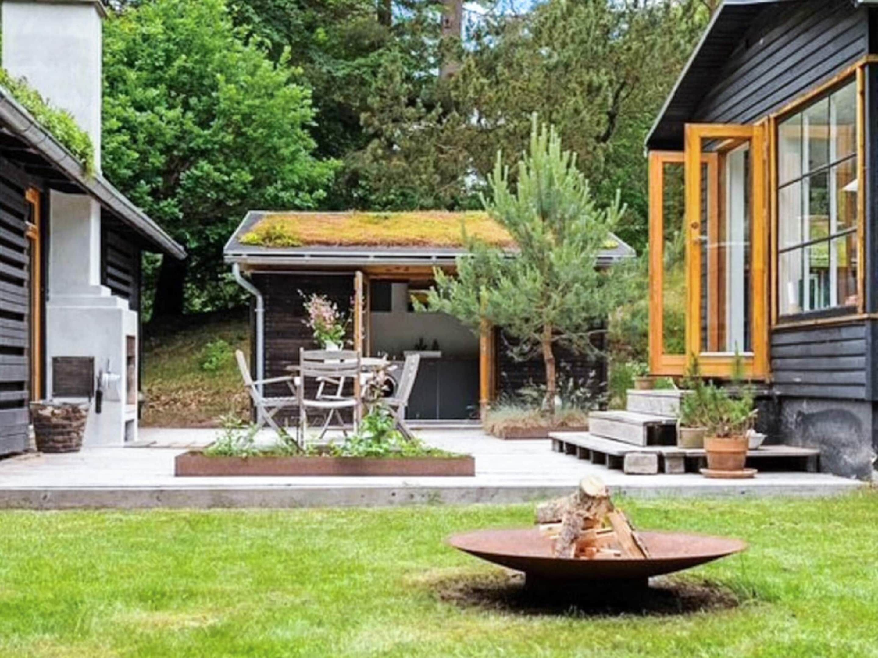 A modern house with a covered patio, a fire pit, and a small garden area.