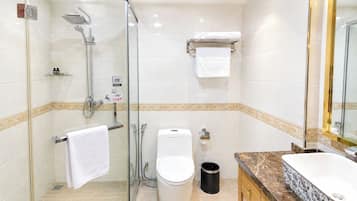 A modern bathroom with a glass-enclosed shower, a toilet, a sink, and a mirror.
