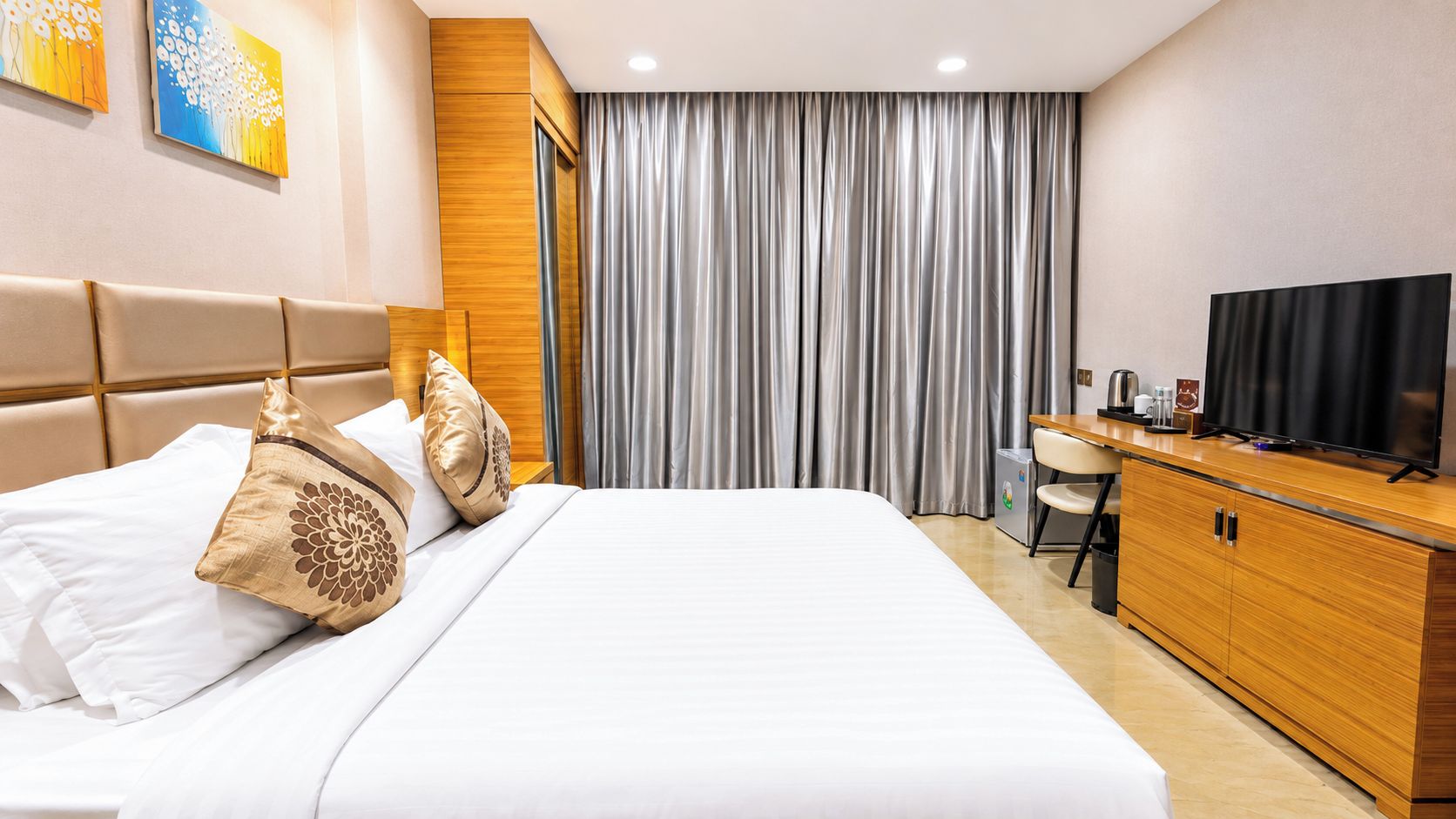 Une chambre d’hôtel avec un lit, un bureau, une télévision et un rideau.